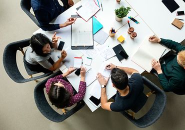 Draufsicht auf mehrere Kollegen an einem Arbeitstisch