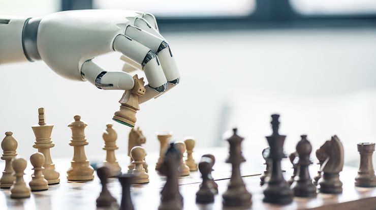 A robotic arm strategically moves a chess piece.