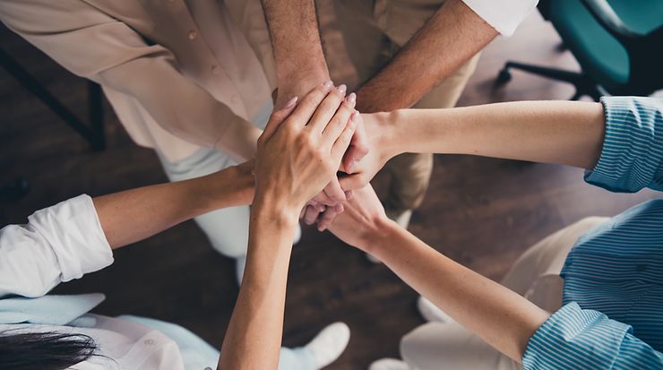Mehrere Personen legen ihre Hände aufeinander als Zeichen von Teamwork