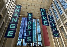 Von Hallendecke hängende Banner mit der Aufschrift "Change Starts Here"