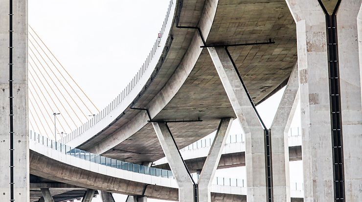 Moderne Betonbrücke mit eleganten Kurven und Seilen vor hellem Himmel