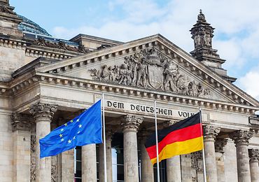Bundestag. Im Vodergrund ist eine EU- und Deutschlandflagge