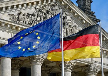 Europäische und deutsche Flagge wehen an Fahnenmast vor dem Reichstagsgebäude